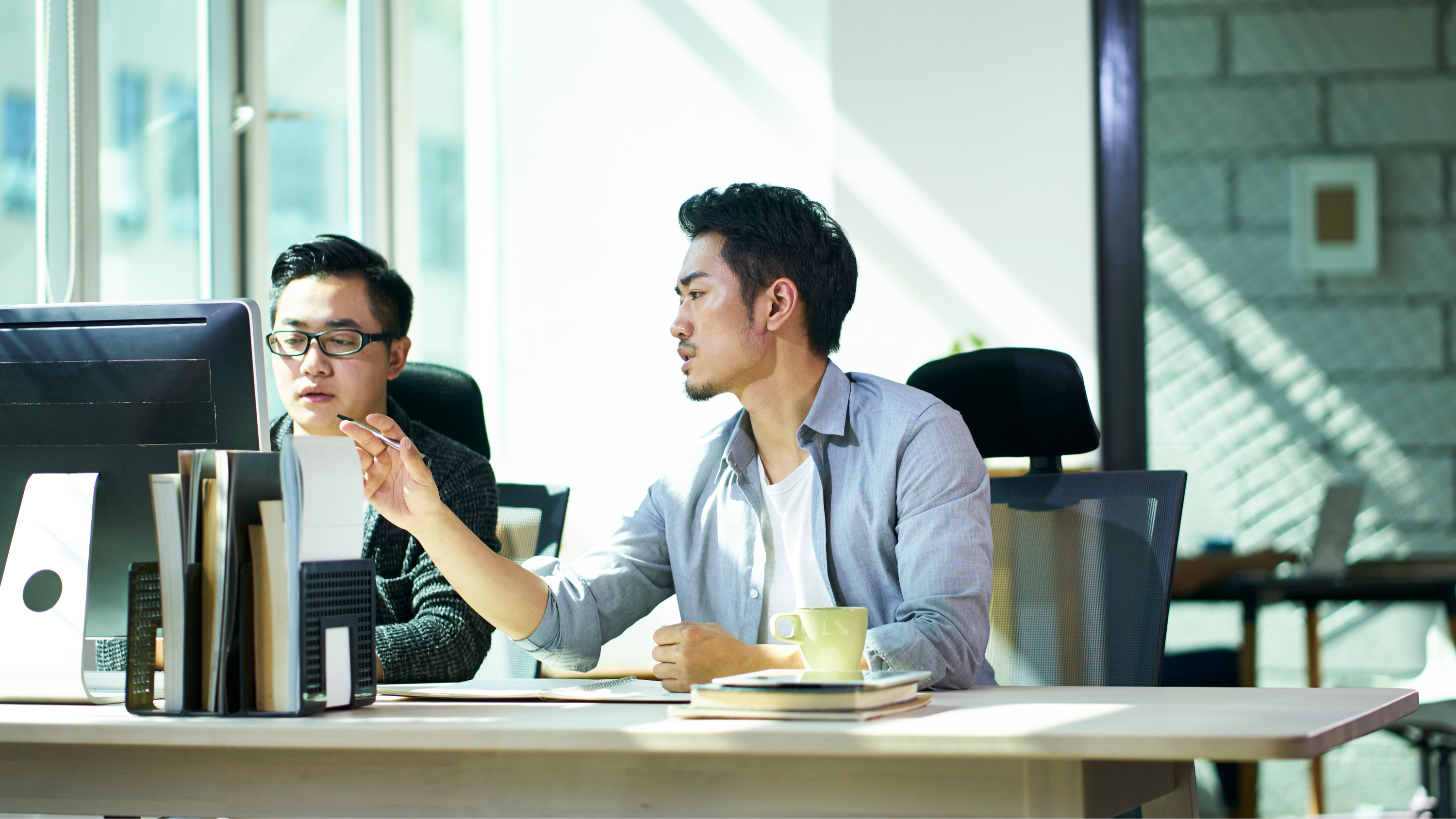 two young asian business people working together in office discussing business